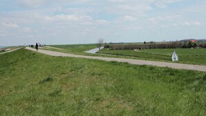 A wide, grassy field with a paved path and a small white structure. - Comfortable and Tasteful Holiday Home Near the Oosterschelde (Kattendijke)