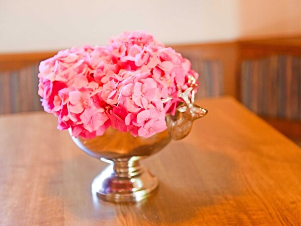 A silver bowl with pink flowers on a wooden table. - Cozy Chalet in Molln With Garden (Molln)