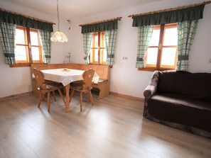 A dining area with a wooden table and chairs, a bench, and a sofa.