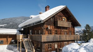 Eine Holzhütte mit Balkon, Treppe und einem mit Schnee bedeckten Dach.
