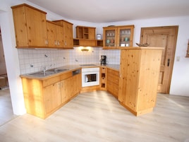 Una cocina compacta con armarios de madera, lavavajillas, horno y cafetera.