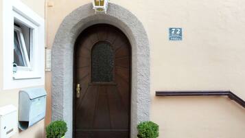 A brown door with a stone archway, a small window, and a street sign indicating the address.
