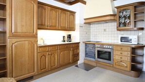 Una cocina con gabinetes de madera, microondas, horno y cafetera.