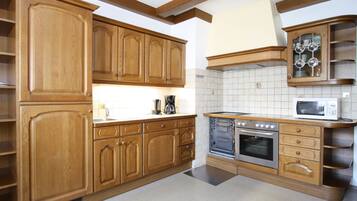 A kitchen with wooden cabinets, a microwave, an oven, and a coffee maker.