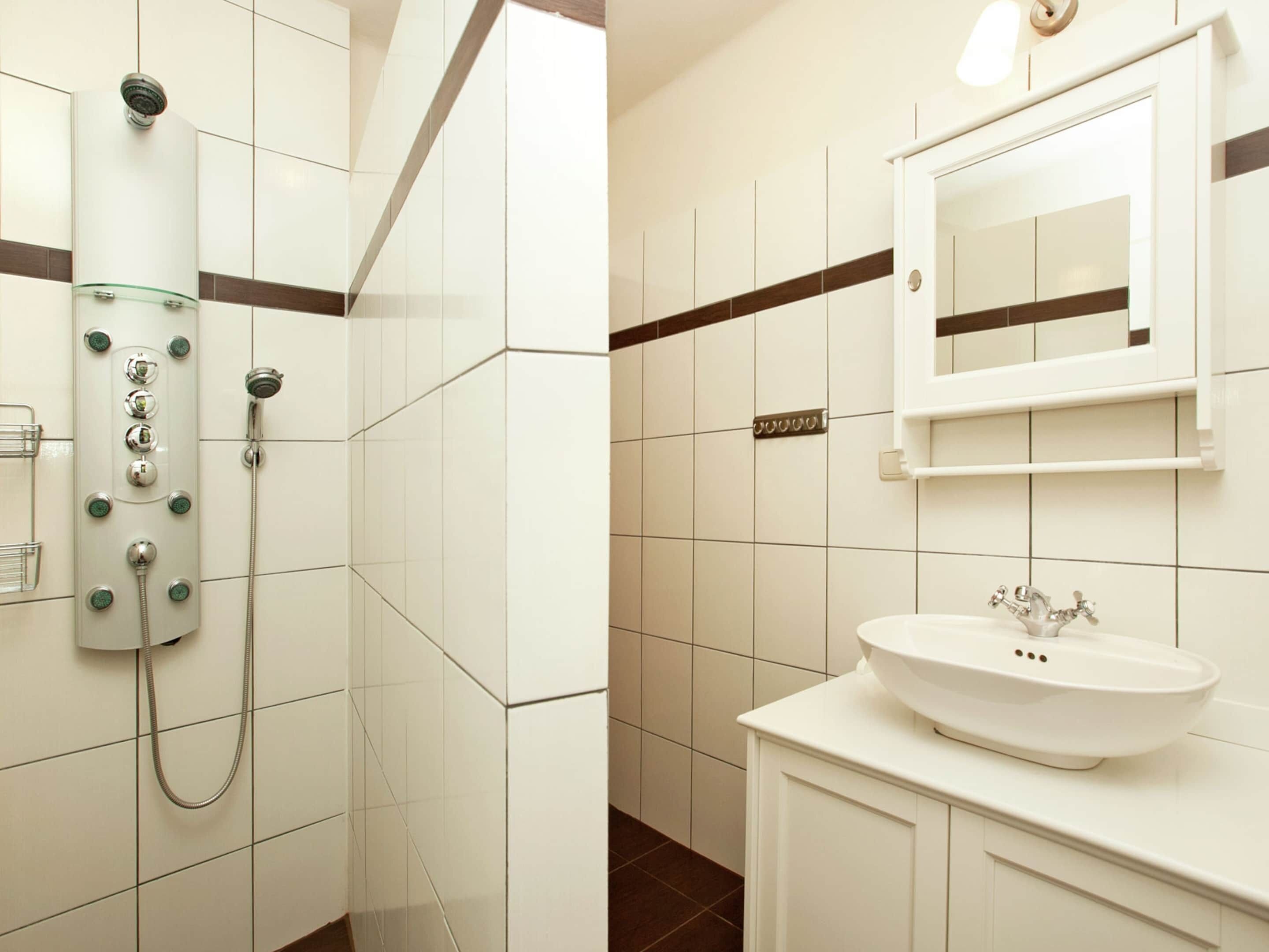 A bathroom with a glass-enclosed shower, a white sink, and a mirror above the sink.