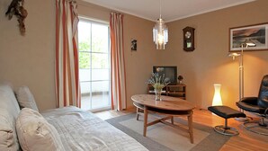 Una sala de estar con sofá, mesa de centro, televisor, reloj y lámpara.