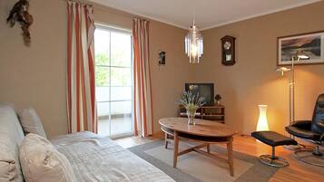 A living room with a sofa, a coffee table, a TV, a clock, and a lamp.