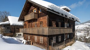 Una cabaña de madera con balcón, rodeada de colinas nevadas.