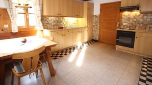 Una cocina con armarios de madera, un salpicadero de azulejos, piso a cuadros y una mesa de comedor con sillas.