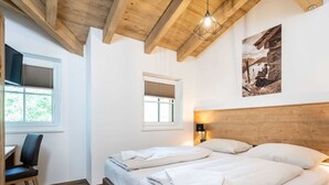 A bedroom with two beds, wooden beams, a desk, and a window. - Chalet in Muhlbach Near Ski Amade (Muehlbach Am Hochkoenig)