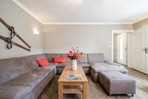 A living room with a sectional sofa, a coffee table, and a vase with flowers. - Alpine Chalet Near Zell am See for 12 (Bruck an der Grossglocknerstrasse)