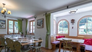 A dining area with wooden furniture, green curtains, and large windows with views of greenery. - Spacious Villa in Zell am See near Ski Area (Zell am See)