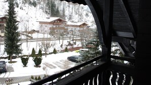 A view from a balcony with a wooden railing, overlooking a snowy landscape with buildings and trees. - Spacious Villa in Zell am See near Ski Area (Zell am See)