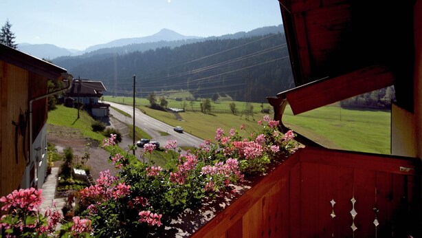 A view from a window overlooking a rural landscape with a road, houses, and mountains in the distance. - Appartment Roswitha (Wagrain)