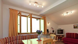 A cozy living room with a sofa, a dining table, and a television. - Appartment Roswitha (Wagrain)