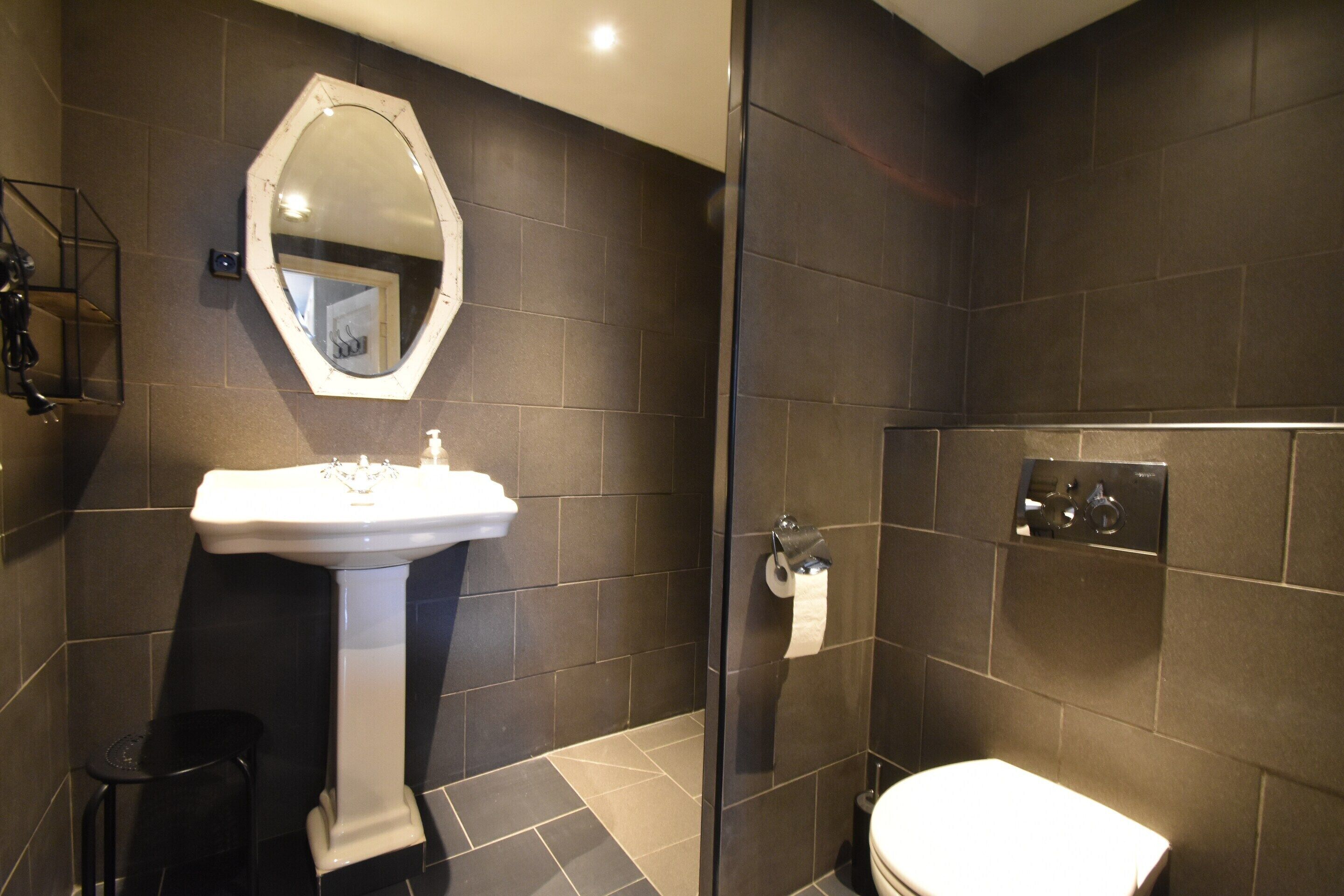 A modern bathroom with a pedestal sink, a toilet, and a glass shower enclosure.