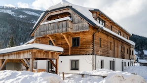 A wooden chalet with a sloped roof and a balcony, surrounded by snow and mountains. - Premium Maisonette Near ski Resorts (Sankt Michael im Lungau)