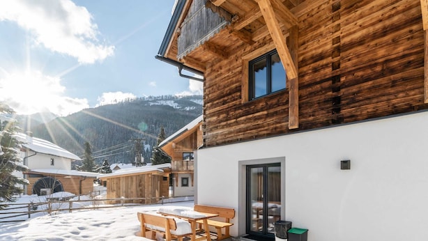 A wooden cabin with a balcony, a table and chairs, and a snow-covered patio. - Premium Maisonette Near ski Resorts (Sankt Michael im Lungau)