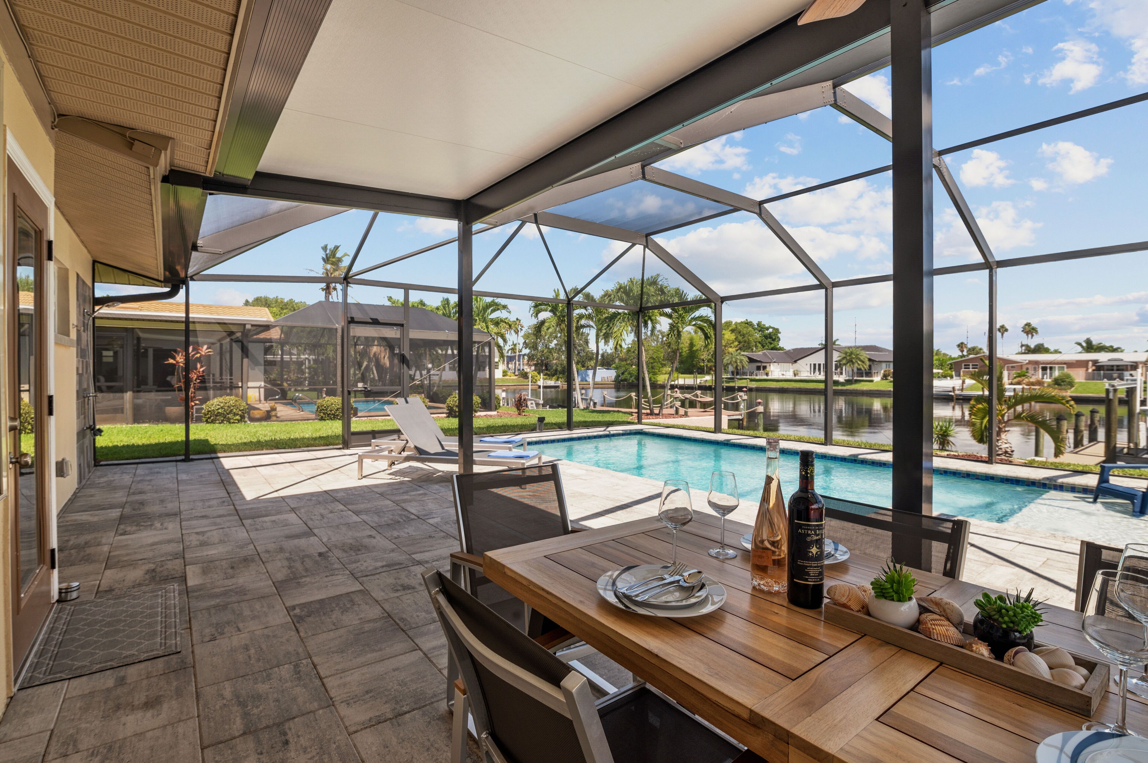 A covered patio with a pool, dining table, and chairs.
