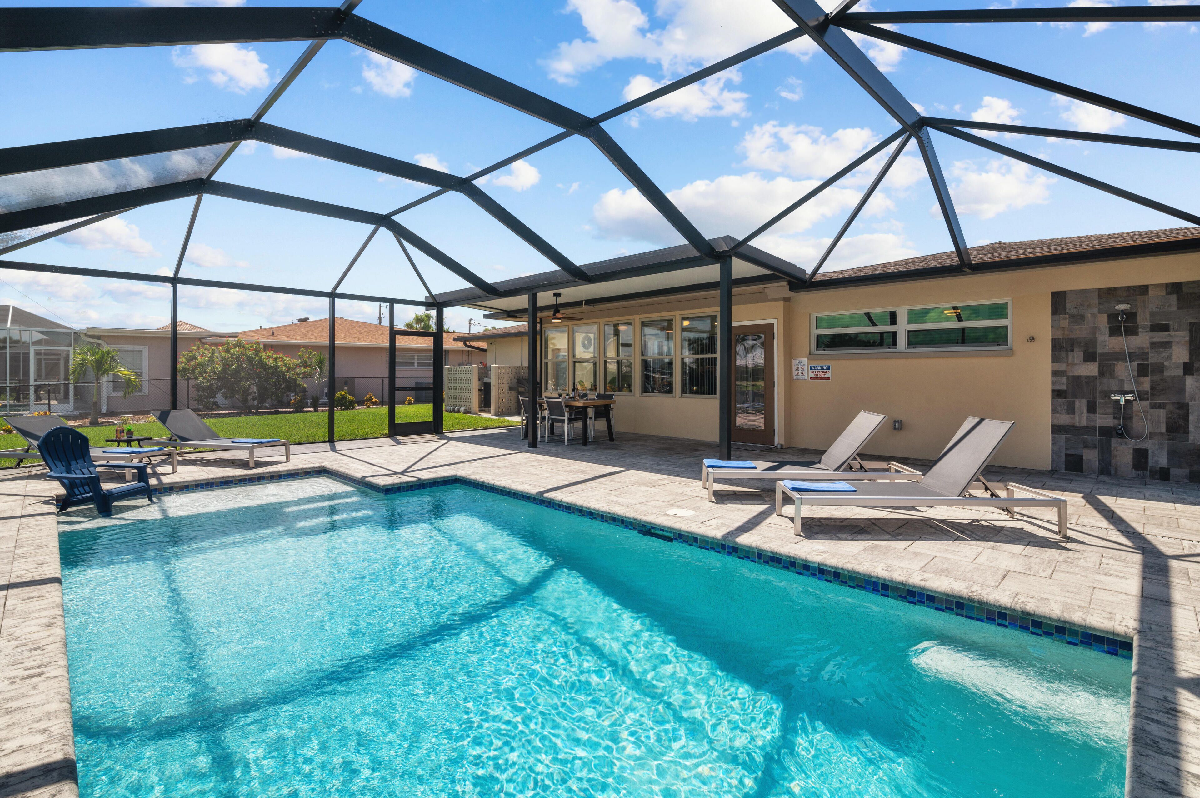 A swimming pool with lounge chairs and a covered area.