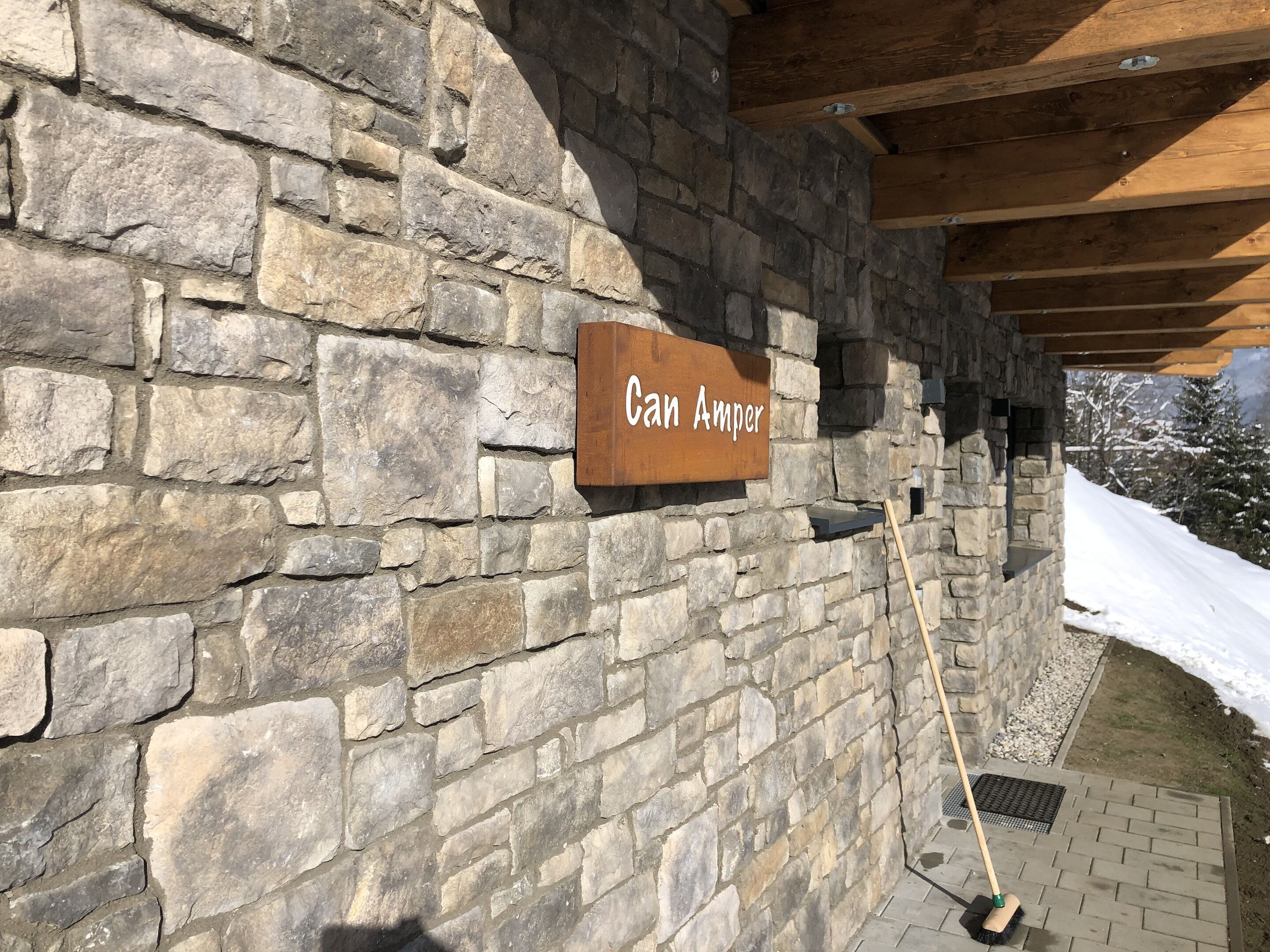 A stone wall with a wooden sign reading "Can Amper."