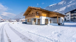 Een houten chalet met een balkon, met een besneeuwde berg op de achtergrond.