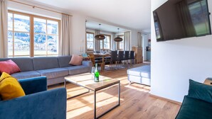 Een moderne woonkamer met een bank, een salontafel en een aan de muur bevestigde televisie.