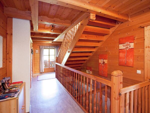 A wooden interior with a staircase, wooden walls, and a door with a window.