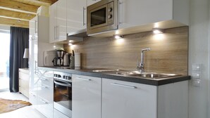 Eine moderne Küche mit weißen Schränken, Edelstahlgeräten und einer Holzrückwand.
