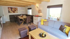 Ein gemütliches Wohnzimmer mit grauem Sofa, Holztisch und einem Essbereich mit Holztisch und Stühlen.