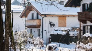 Ein schneebedecktes Gebäude mit einem Holzbalkon und einer Hirschsilhouette an der Wand.