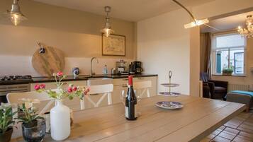Une cuisine moderne avec une table en bois, des chaises et un coin repas. On y trouve une cuisinière, un évier et divers appareils de cuisine.