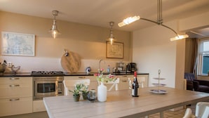 Een moderne keuken met een eethoek, met een houten tafel, witte stoelen en een koffieapparaat.