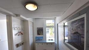 Een smalle gang met een witte kast, een klein raam en een radiator.