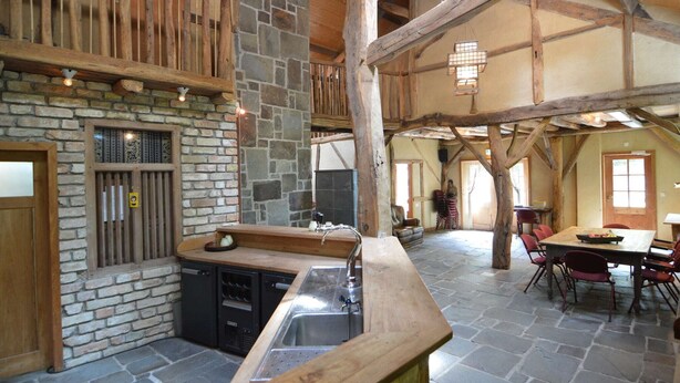 A rustic interior with a stone fireplace, wooden beams, and a stone floor. - Lodge Maasduinen Near National Park (Wellerlooi)