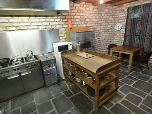 A kitchen with a brick wall, a wooden table, and a stove.
