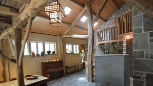 A rustic interior with a stone fireplace, wooden beams, and a stone floor. - Lodge Maasduinen Near National Park (Wellerlooi)