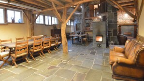 A rustic interior with a stone floor, wooden furniture, a stone fireplace, and a wooden ceiling structure. - Lodge Maasduinen Near National Park (Wellerlooi)