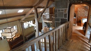 A rustic interior with exposed wooden beams, stone walls, and a wooden staircase. - Lodge Maasduinen Near National Park (Wellerlooi)