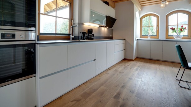 A modern kitchen with wooden beams, built-in appliances, and large windows. - Chalet in Mauterndorf Near Ski Slopes (Mauterndorf)