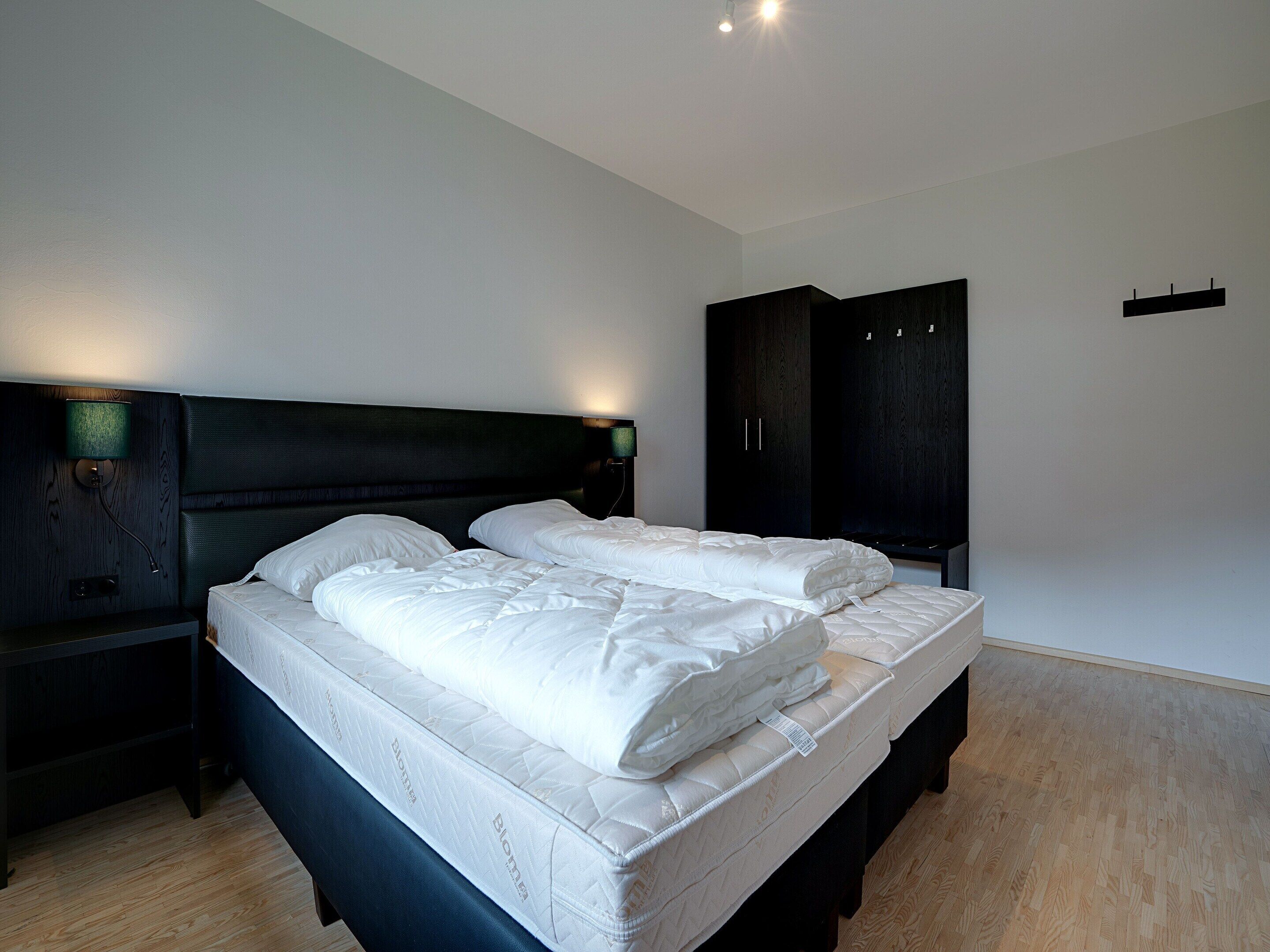 A bedroom with a bed, nightstands, and a wardrobe.