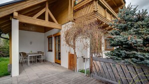 A wooden deck with a table and chairs, a wooden fence, and a coniferous tree. - Chalet in Mauterndorf Near Ski Slopes (Mauterndorf)