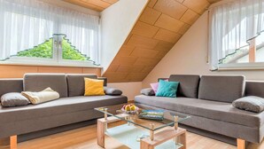 A modern loft apartment with two grey sofas, a glass coffee table, and wooden flooring. - Apartment in Marktrodach With Sauna & Garden (Marktrodach)