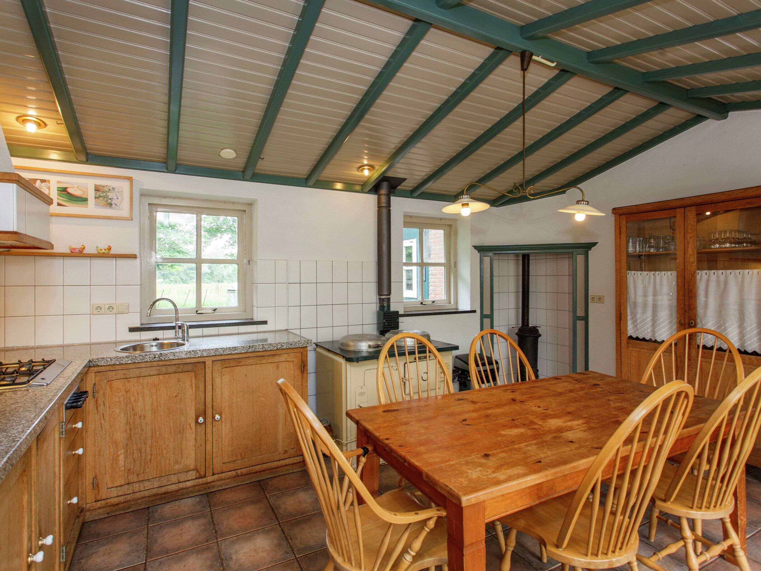 A kitchen with wooden cabinets, a granite countertop, a stove, a sink, and a dining table with chairs.