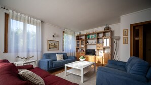 Un soggiorno con un divano blu, un tavolino da caffè bianco e una libreria.