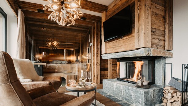 Una sala de estar acogedora con chimenea, sillón de cuero y una lámpara moderna.