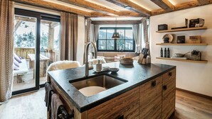 Una cocina con una isla grande, vigas de madera y vistas a un paisaje nevado.