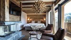 Un dormitorio moderno con una cama grande, una chimenea, un sillón de cuero y vistas al exterior.