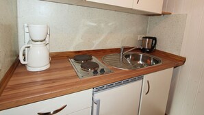 Pieni, käytännöllinen keittiönurkkaus, jossa on kahvinkeitin, vedenkeitin ja liesi.