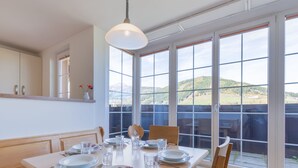 A dining area with a table set for four, large windows offering a view of the outdoors, and a hanging light fixture above the table. - Modern Apartment in St Margarethen With Mountain View (Sankt Margarethen im Lungau)